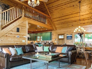 A wooden cabin interior with a living area, staircase, and kitchen.