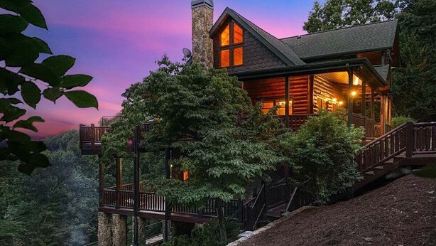 Eine Blockhütte mit Balkon, umgeben von Bäumen und Blick auf die Landschaft.