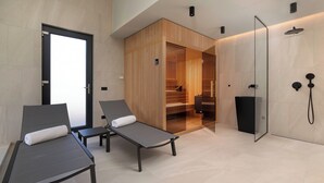 A modern spa room with two lounge chairs, a glass-enclosed shower area, and a wooden sauna. - Villa Cesarica with heated pool, indoor pool & sauna (Kvarner - Vrh) (Vrh)