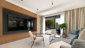 A modern living room with a flat-screen TV, comfortable seating, a coffee table, and a potted plant. - Villa Cesarica with heated pool, indoor pool & sauna (Kvarner - Vrh) (Vrh)