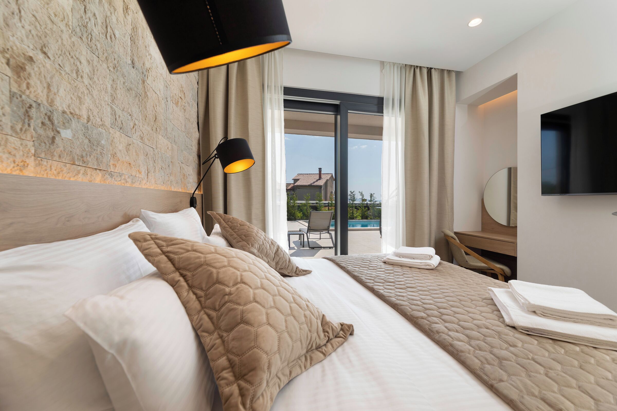 A hotel room with a large bed, a desk, a flat-screen TV, and a view of the outdoors.