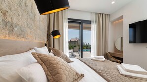 A hotel room with a large bed, a desk, a flat-screen TV, and a view of the outdoors. - Villa Cesarica with heated pool, indoor pool & sauna (Kvarner - Vrh) (Vrh)