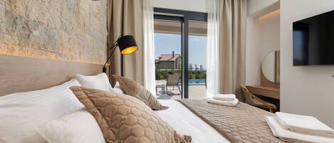A hotel room with a large bed, a desk, a flat-screen TV, and a view of the outdoors.
