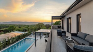 A modern outdoor balcony with a pool, seating area, and a view of the landscape. - Villa Cesarica with heated pool, indoor pool & sauna (Kvarner - Vrh) (Vrh)