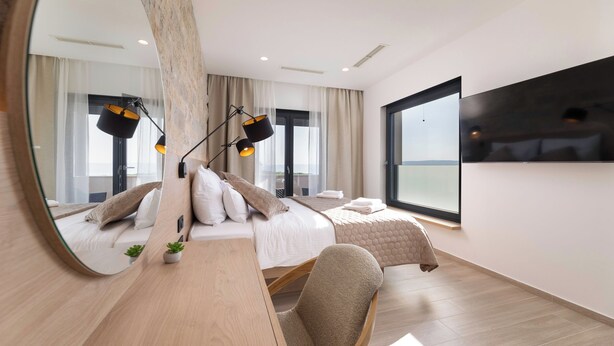 A modern hotel room with a large bed, a desk, a chair, a mirror, and a large window. - Villa Cesarica with heated pool, indoor pool & sauna (Kvarner - Vrh) (Vrh)