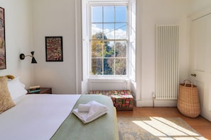 A bedroom with a bed, a window, a radiator, a bedside table, and a wall-mounted lamp. - LUXURY HERITAGE TOWNHOUSE ︱KING BED ︱NEAR BOTANICS (Edinburgh)