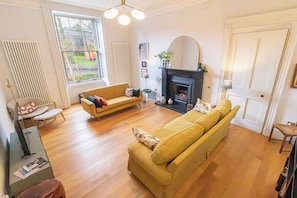 A living room with a sofa, a fireplace, and a radiator. - LUXURY HERITAGE TOWNHOUSE ︱KING BED ︱NEAR BOTANICS (Edinburgh)