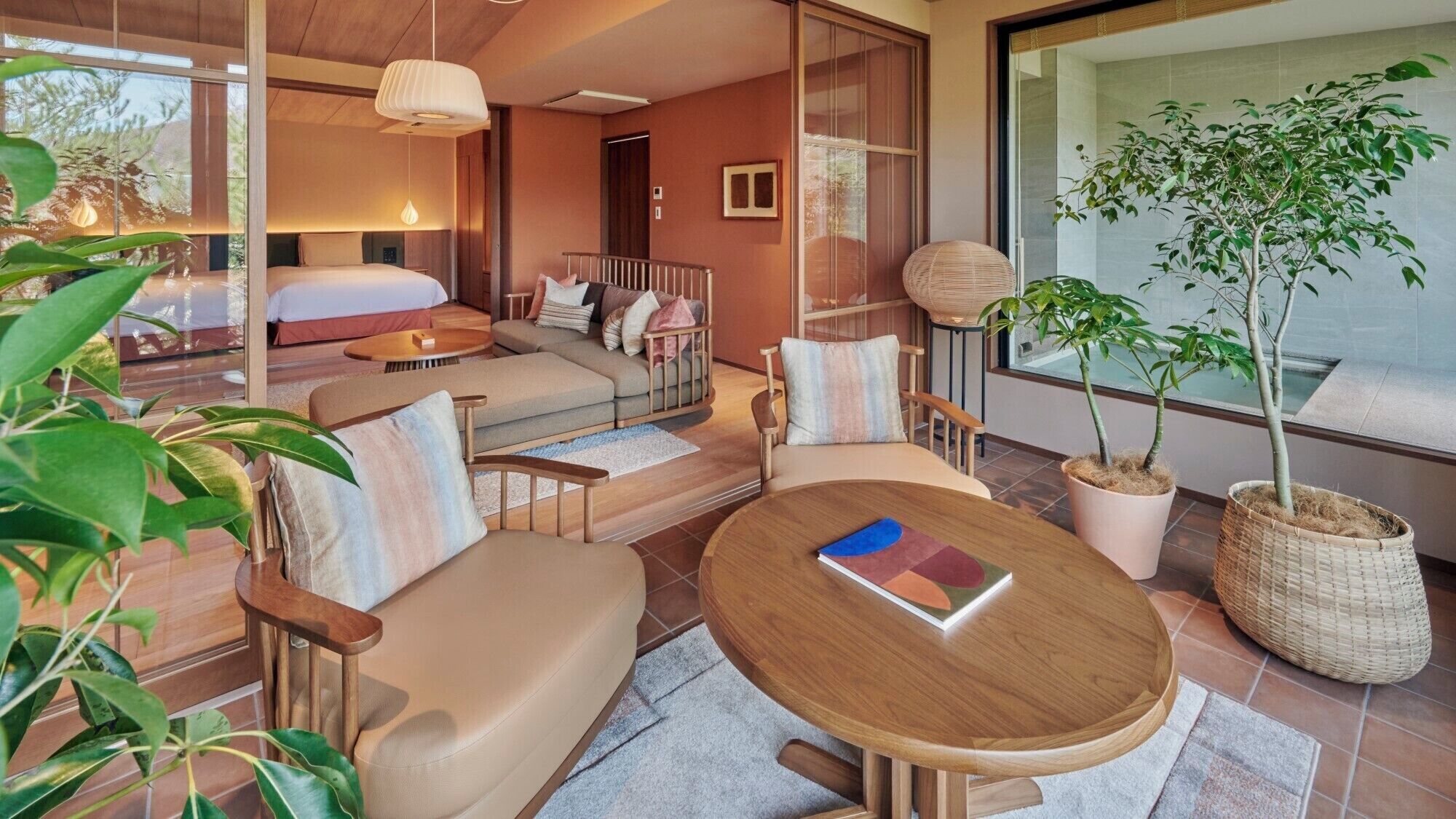 Une chambre d’hôtel moderne, équipée d’un lit, d’un canapé, d’une table à manger et de plantes en pot.