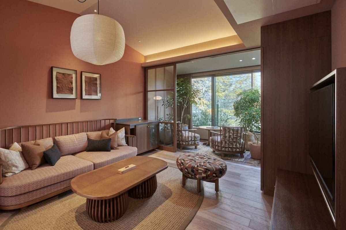 Uma sala de estar moderna com um sofá, uma mesa de centro de madeira e uma janela grande com vista para o exterior.