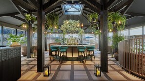 A modern bar area with a central island, bar stools, hanging plants, and a wooden floor. - Fufu Karuizawa (Karuizawa)