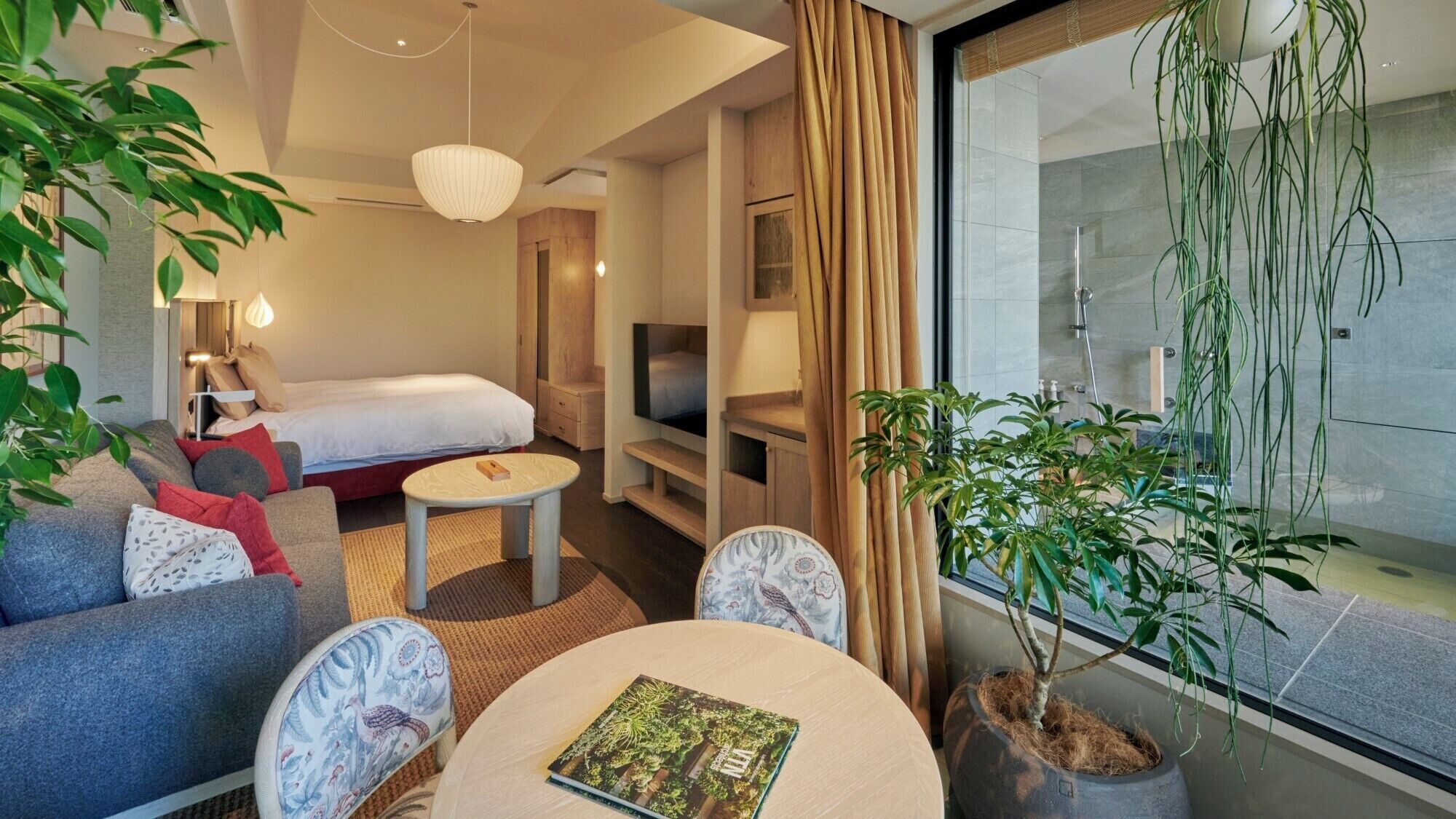 Une chambre d’hôtel moderne équipée d’un lit, d’un canapé, d’une télévision et de plantes en pot.
