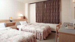 Ein Hotelzimmer mit zwei Betten, einem Schreibtisch, einem Stuhl, einer Lampe und einem großen Fenster mit Vorhängen.