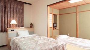 Ein Hotelzimmer mit zwei Betten, einem Nachttisch mit Lampe, einer kleinen Pflanze und einem Fernseher.