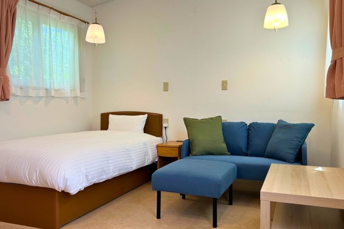 Une chambre à coucher comprenant un lit, un canapé, une petite table et deux lampes suspendues.