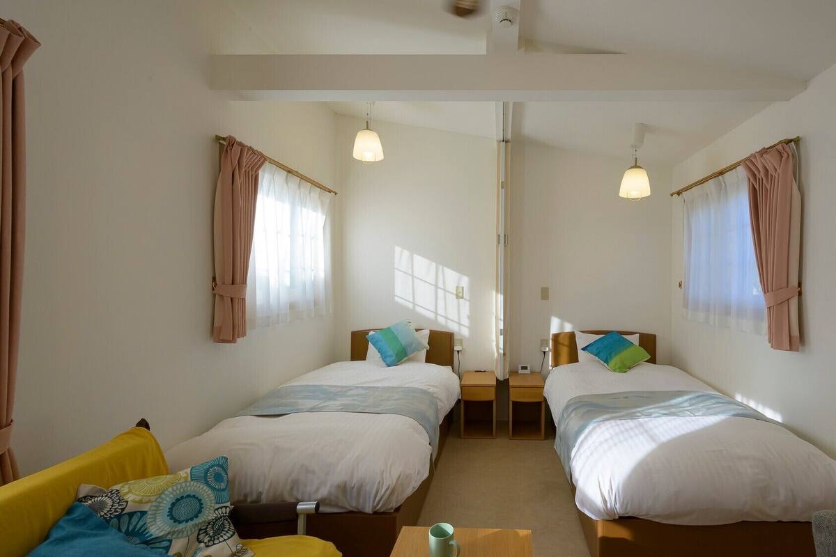 A room with two beds, a sofa, a coffee table, and a ceiling fan.