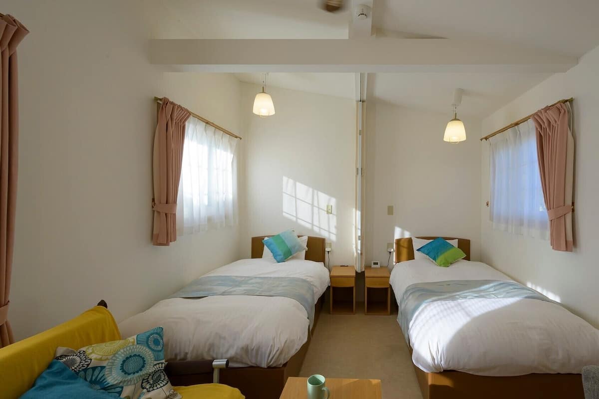A room with two beds, a sofa, a coffee table, and a ceiling fan.