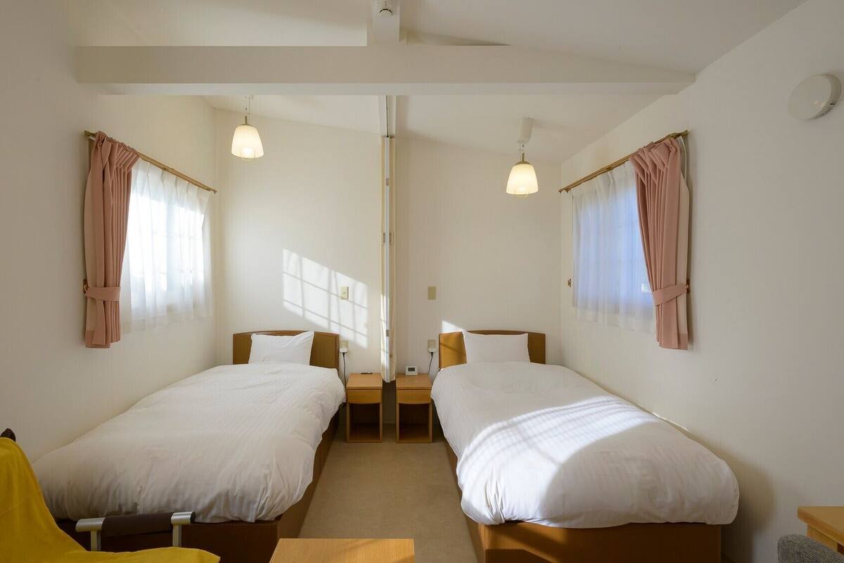 A room with two beds, a small table, and a chair.