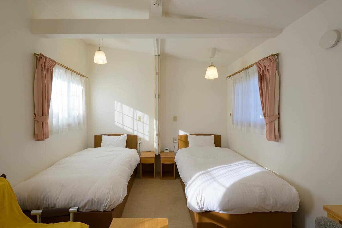 A room with two beds, a small table, and a chair.