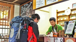 A reception desk with a clock, a signboard, and a shelf with books. - Sounkyo Hostel (Kamikawa)