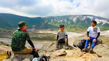 Three people sitting on rocks with a mountainous landscape in the background.