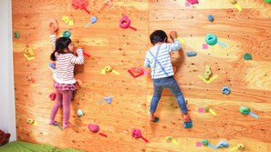 Two children climbing a wooden wall with various colorful holds. - Sounkyo Hostel (Kamikawa)