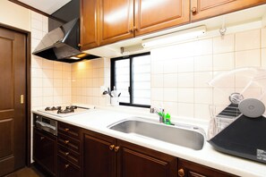 Een keuken met houten kastjes, een roestvrijstalen spoelbak en een raam.