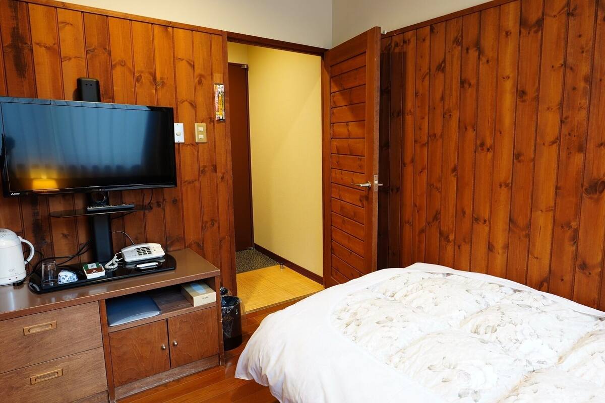 A hotel room with a bed, a television, a coffee maker, and a desk with a telephone.