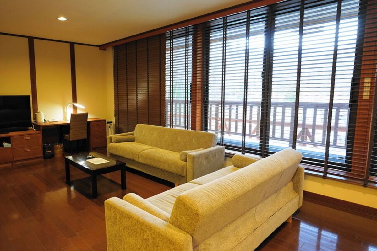 A living room with a sofa, a coffee table, a TV, and a desk with a lamp.