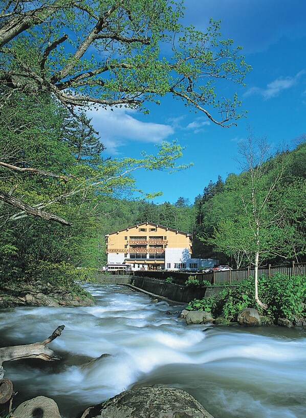 Un edificio de fachada amarilla, con un balcón y un río que fluye delante.