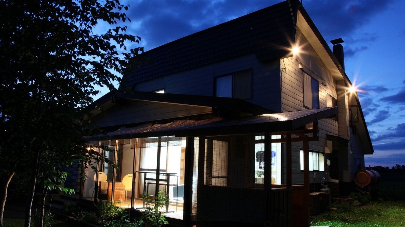 Een modern huis met een grote glazen voorgevel, een overdekt terras en een zichtbare schoorsteen.