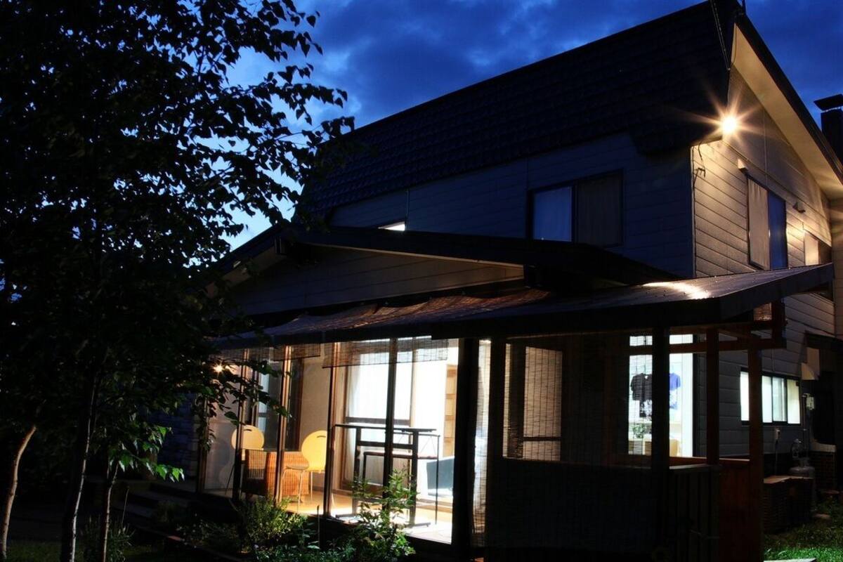 Una casa moderna con un'ampia vetrata, un portico coperto e un camino ben visibile.