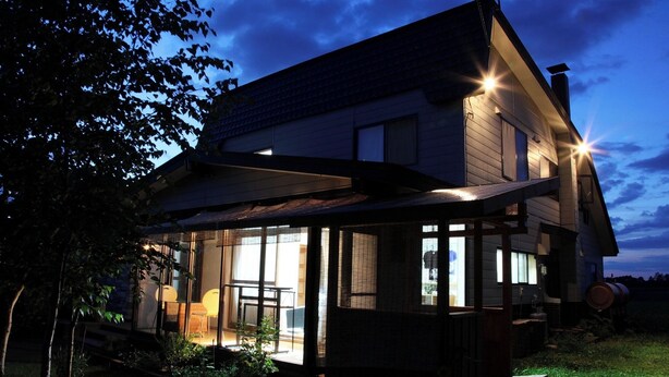 A modern two-story house with a covered patio, large windows, and a visible chimney.