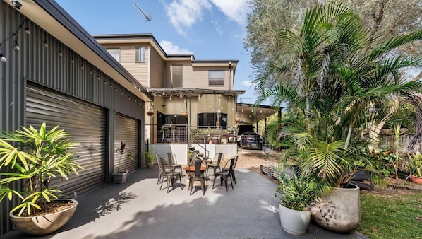 A residential property with a patio, outdoor seating, and potted plants.