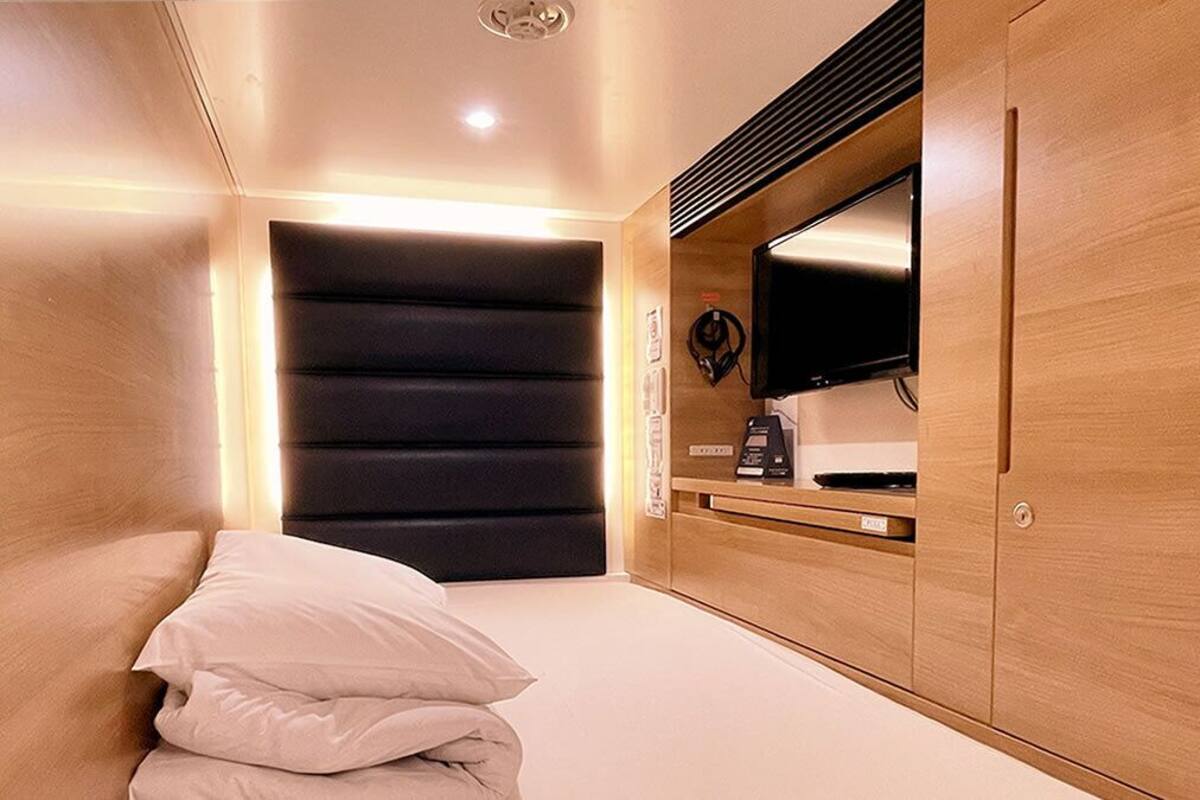A bedroom with a bed, a TV, a desk, and a wardrobe.