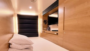A bedroom with a bed, a TV, a desk, and a wardrobe. - Capsule Hotel Topos Sendai Station Nishiguchi (Sendai)