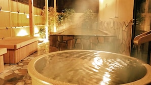 A hot spring bath area with stone flooring, wooden benches, and a stone wall. - Capsule Hotel Topos Sendai Station Nishiguchi (Sendai)