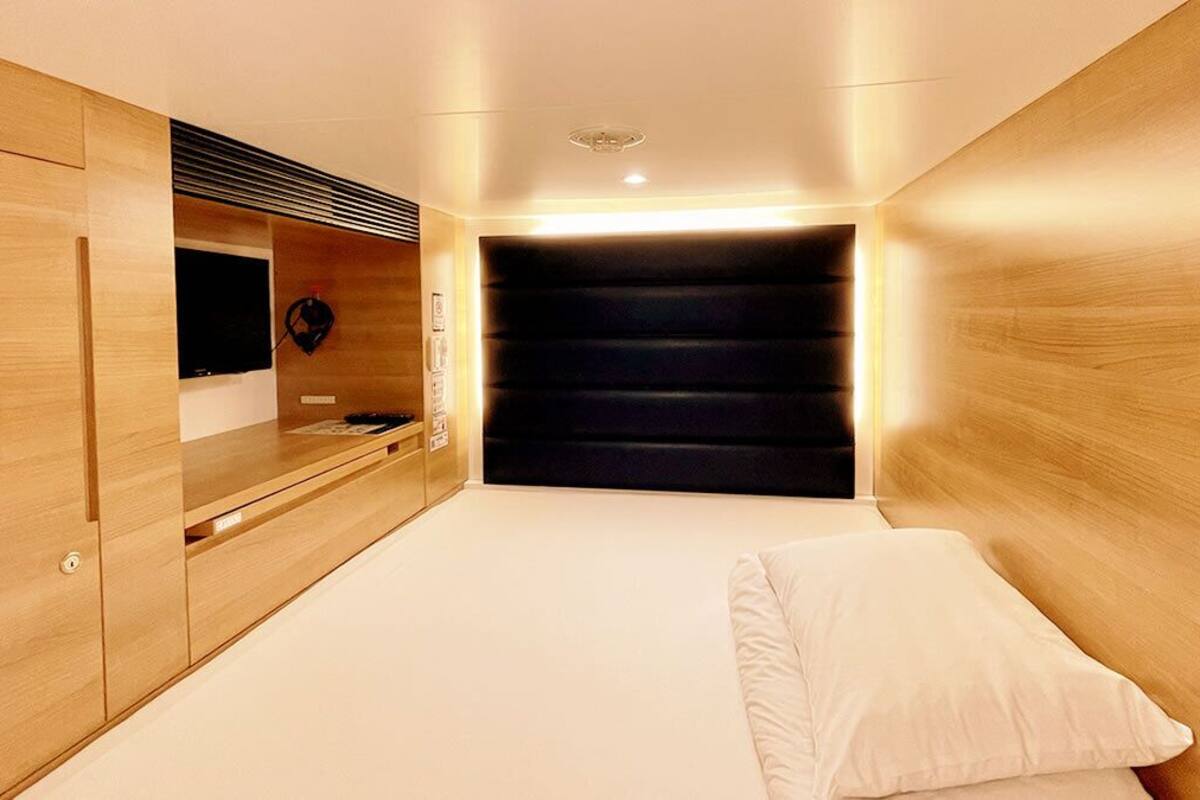 A bedroom with a bed, wooden wardrobe, and a television.