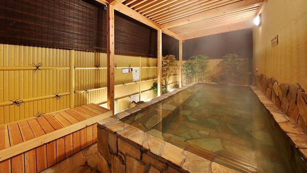 A hot spring bath area with wooden benches and stone walls. - Capsule Hotel Topos Sendai Station Nishiguchi (Sendai)