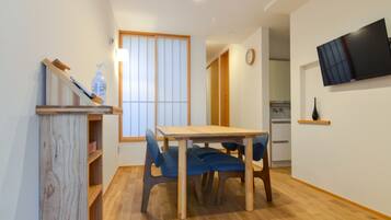 A compact living space with a dining table, chairs, a TV, and a kitchen area.