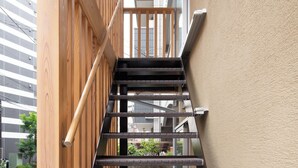 A modern staircase with wooden accents and glass railings, leading to an upper level. - Chiisana Kinoie (Tokyo)