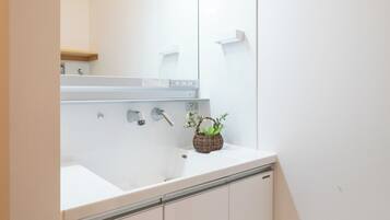 A bathroom with a white sink, mirror, and wooden floor.
