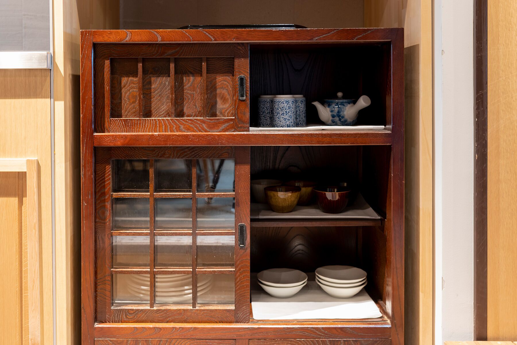 A wooden cabinet with multiple shelves containing various kitchen items.