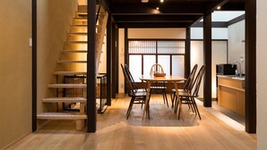 A dining area with a wooden table and chairs, a staircase, and a kitchen area with a sink and microwave. - Nishijinkita Hagi Ajisai (Kyoto)