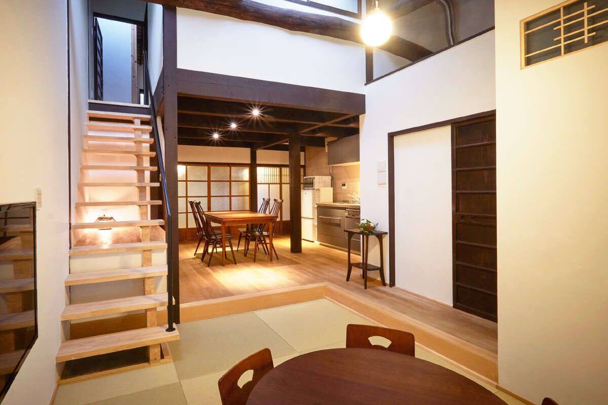 Ein modernes Interieur mit Treppe, Essbereich, Küche und einem großen Fenster.