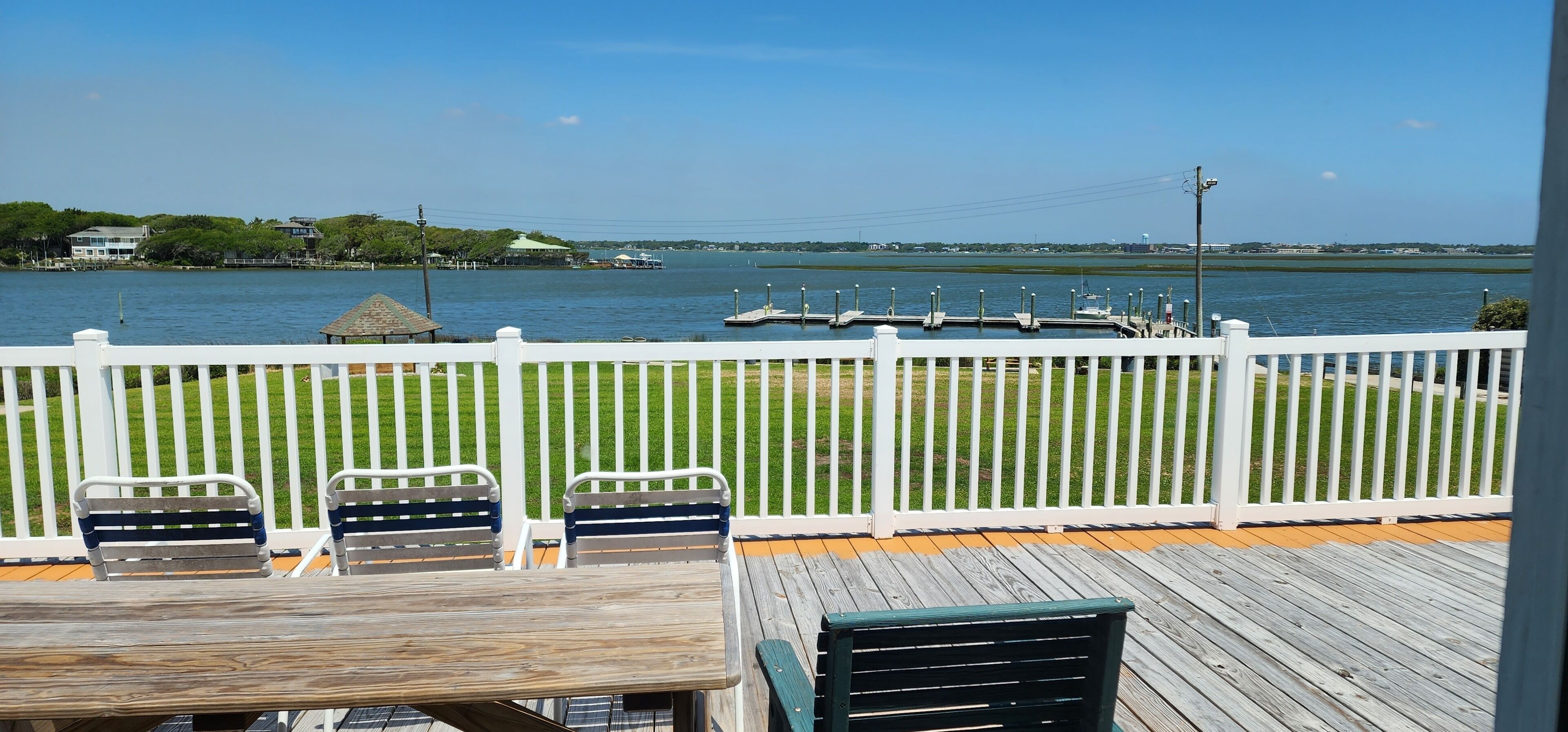 A deck with a view of a lake, docked boats, and a grassy area.