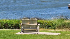 A bench with two trash bins in front of a body of water. - Cozy studio with refreshing AC, pool, and 3-minute walk to the beach (Atlantic Beach)