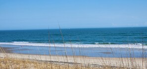Ein Strand mit Wellen, einem klaren Himmel und Booten in der Ferne.
