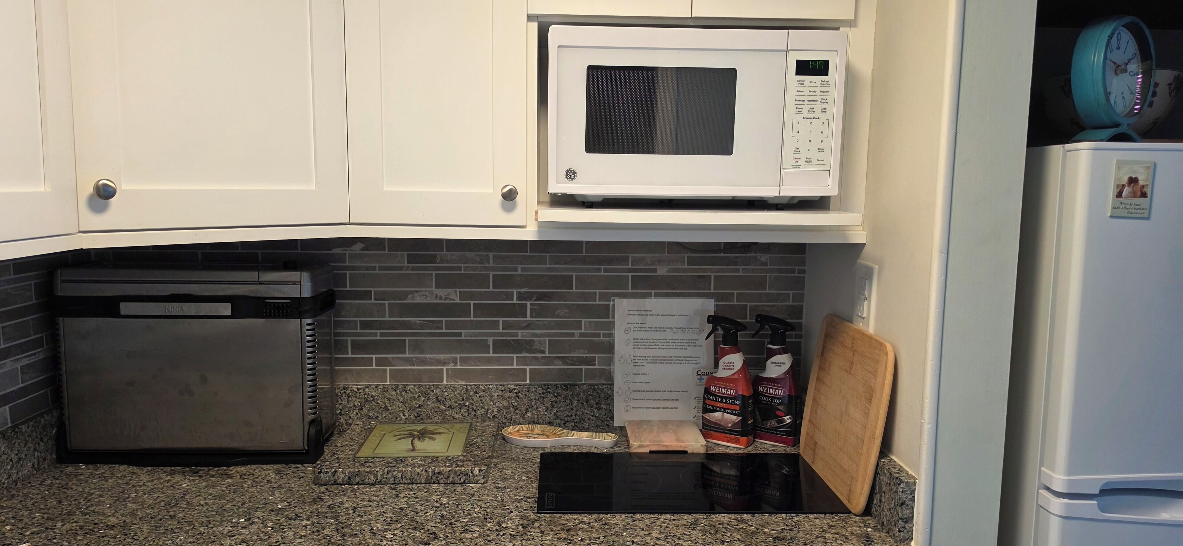 A kitchen with a microwave, a coffee maker, and cleaning supplies.