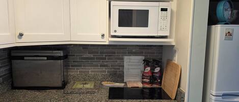A kitchen with a microwave, a coffee maker, and cleaning supplies.