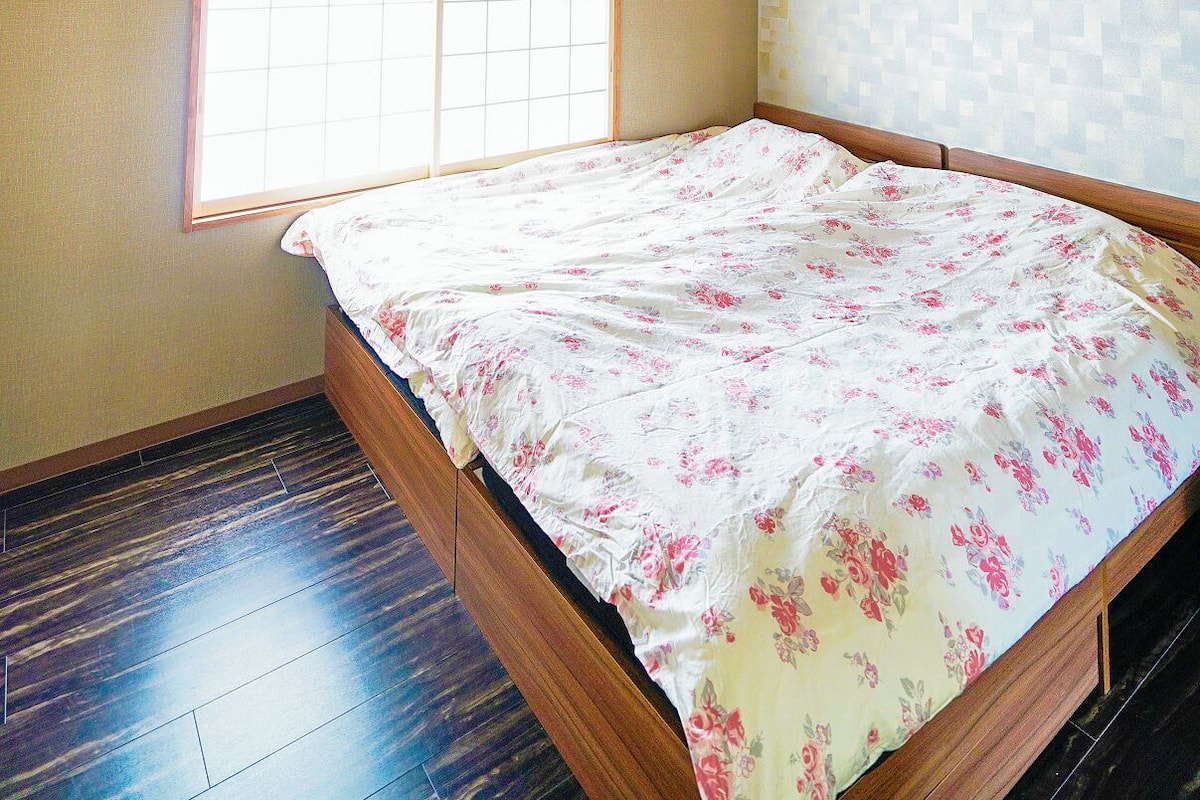 Un dormitorio con una cama de madera, una ventana y un ventilador de techo.